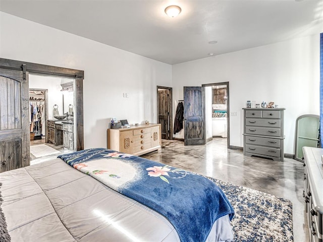 912 Ash NE, Piedmont, OK 73078 - bedroom featuring concrete flooring, a barn door, baseboards, a walk in closet, and ensuite bath