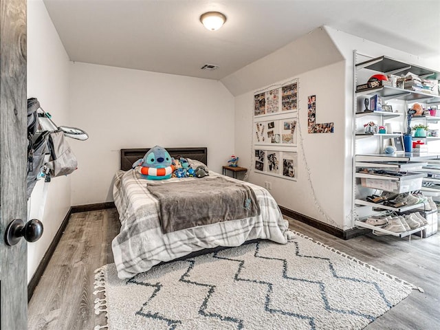912 Ash NE, Piedmont, OK 73078 - bedroom with baseboards, visible vents, vaulted ceiling, and wood finished floors