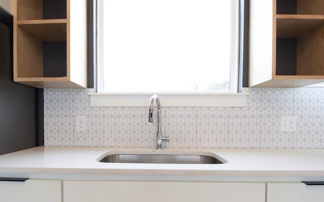 kitchen featuring white cabinetry, sink, and tasteful backsplash