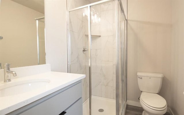 bathroom with vanity, a shower with shower door, and toilet