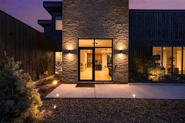 exterior entry at dusk featuring stone siding