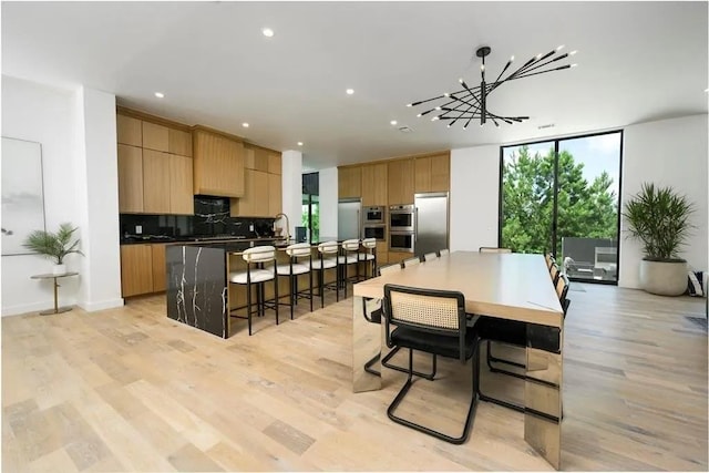 kitchen featuring a large island, light wood-style flooring, appliances with stainless steel finishes, expansive windows, and backsplash