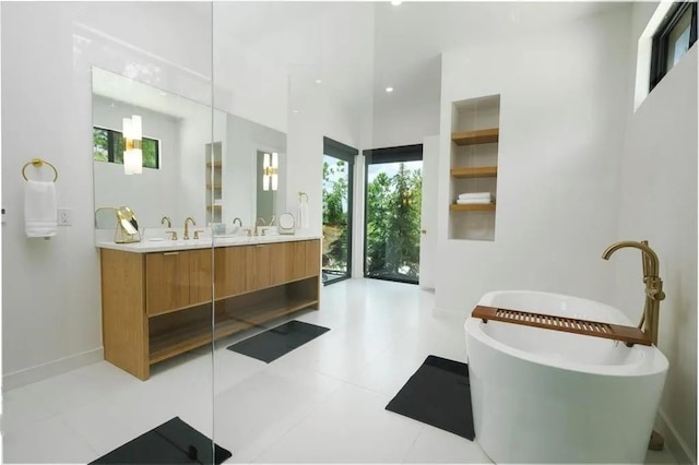 bathroom featuring a freestanding bath, double vanity, and baseboards