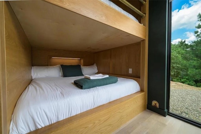 bedroom featuring light wood-style flooring and wooden walls