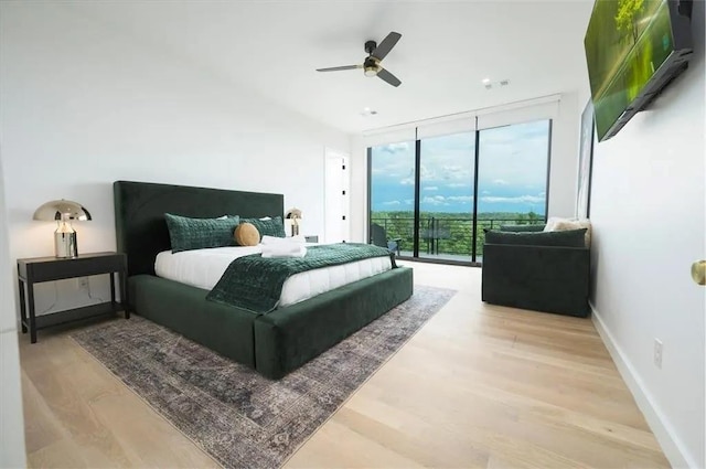 bedroom featuring light wood finished floors, baseboards, a ceiling fan, access to exterior, and expansive windows