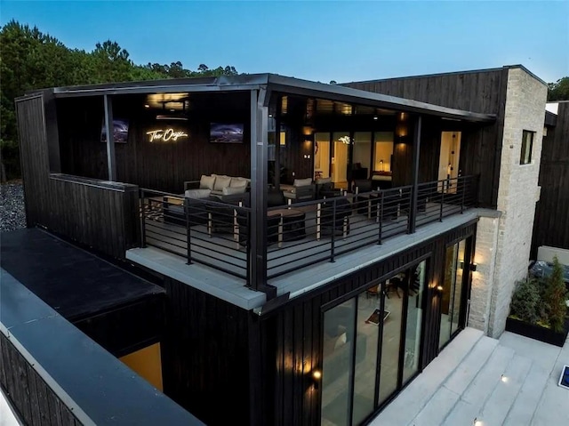 back of house at dusk featuring a balcony