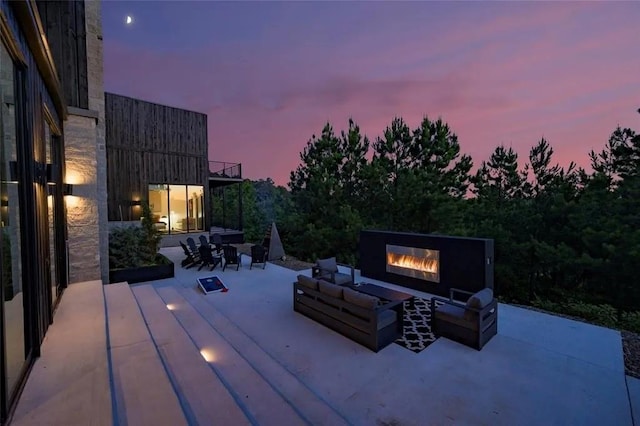 patio terrace at dusk featuring an outdoor living space with a fireplace