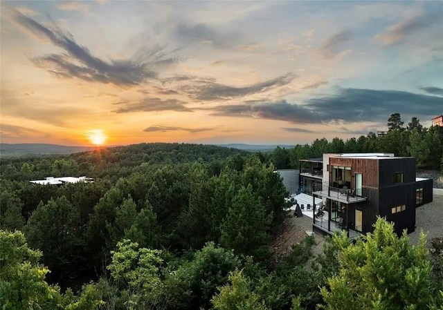 aerial view at dusk featuring a view of trees