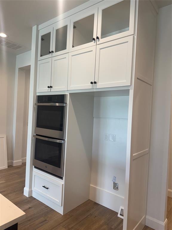 12804 Cobblestone Curve Rd, Oklahoma City, OK 73142 - kitchen with stainless steel double oven, white cabinetry, dark wood finished floors, glass insert cabinets, and light countertops