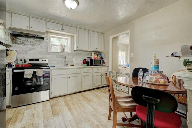 kitchen with appliances with stainless steel finishes, light countertops, under cabinet range hood, white cabinetry, and a sink