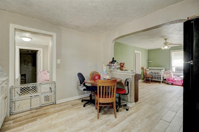 dining area featuring baseboards, wood tiled floor, arched walkways, and a textured ceiling