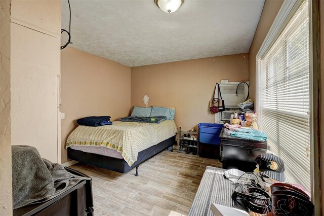 bedroom with a textured ceiling and light wood finished floors