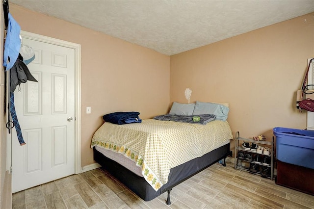 bedroom with a textured ceiling and wood tiled floor