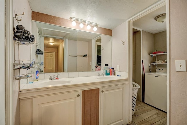 bathroom featuring double vanity, washer / dryer, a sink, and wood finished floors