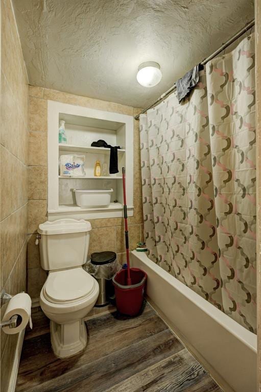 full bath with tile walls, toilet, shower / bath combo, a textured ceiling, and wood finished floors