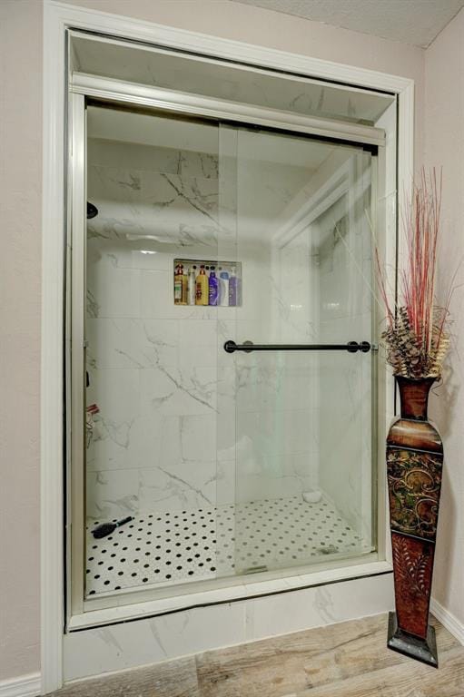 full bathroom featuring a shower stall, baseboards, and wood finished floors