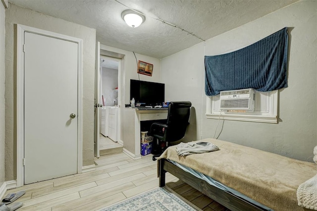 bedroom featuring wood tiled floor, a textured ceiling, separate washer and dryer, and cooling unit