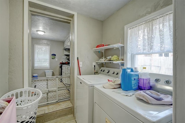 washroom featuring laundry area, light wood-style flooring, a wealth of natural light, and washer and dryer