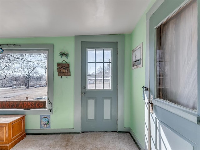 doorway with light carpet, a wealth of natural light, and baseboards