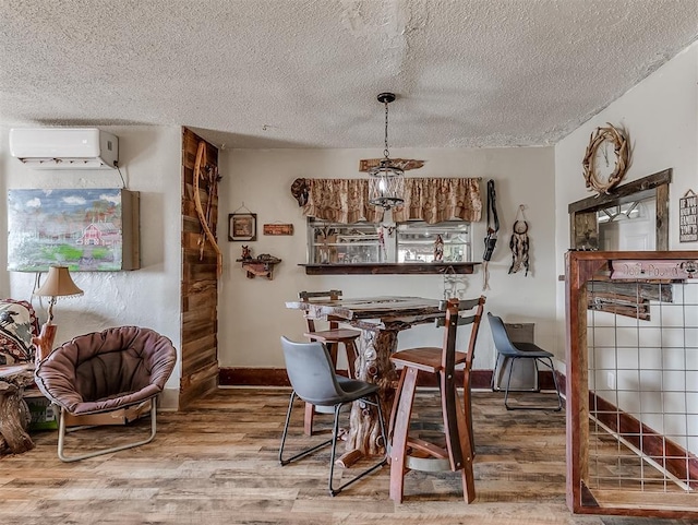 dining space featuring a textured ceiling, wood finished floors, and a wall mounted AC