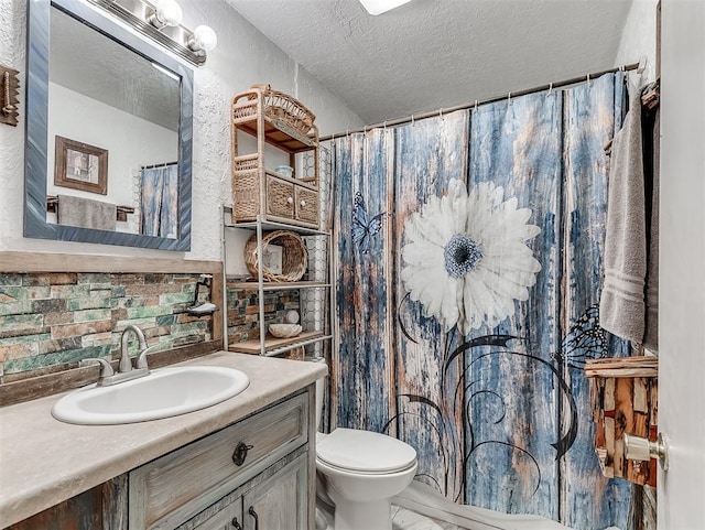 full bathroom with a textured ceiling, toilet, and vanity