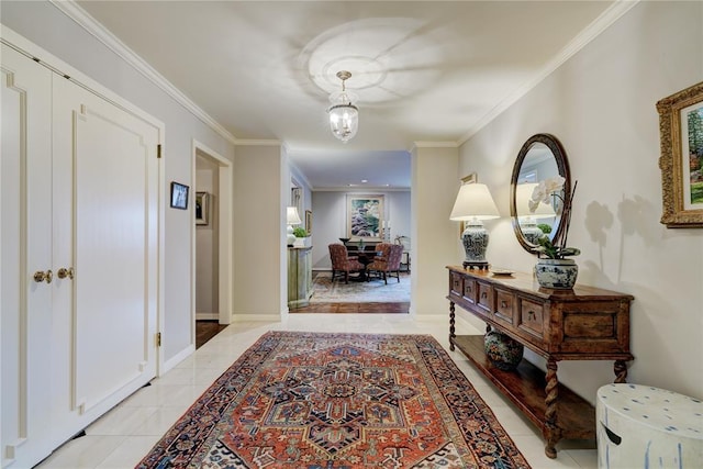 hall with light tile patterned floors, baseboards, a chandelier, and crown molding