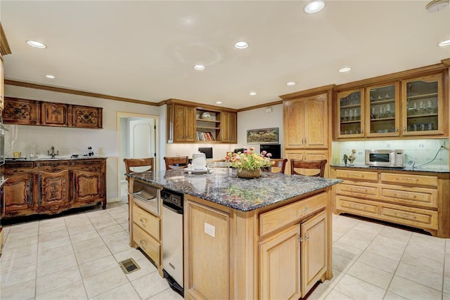 kitchen with light tile patterned flooring, ornamental molding, a center island, dark stone countertops, and glass insert cabinets