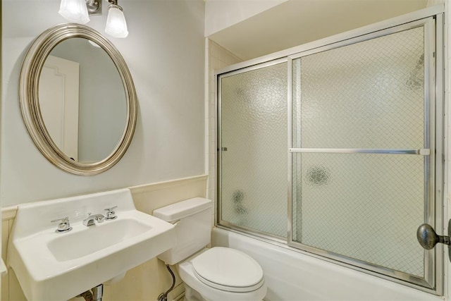 bathroom with enclosed tub / shower combo, a sink, and toilet