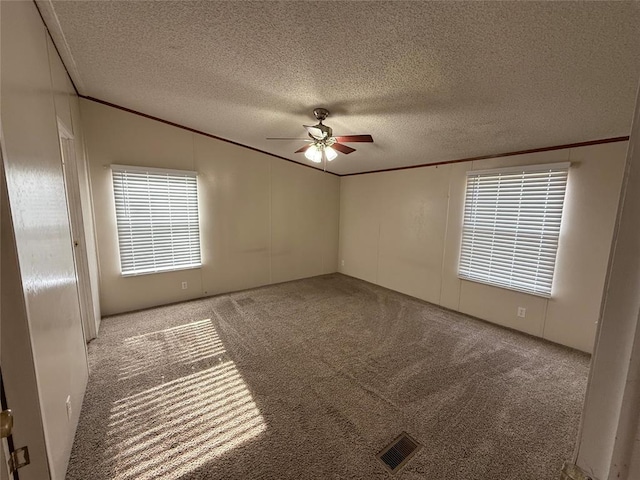 empty room featuring a textured ceiling, ornamental molding, light carpet, and ceiling fan