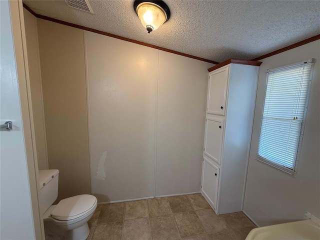 bathroom featuring toilet, crown molding, tile patterned floors, and a textured ceiling