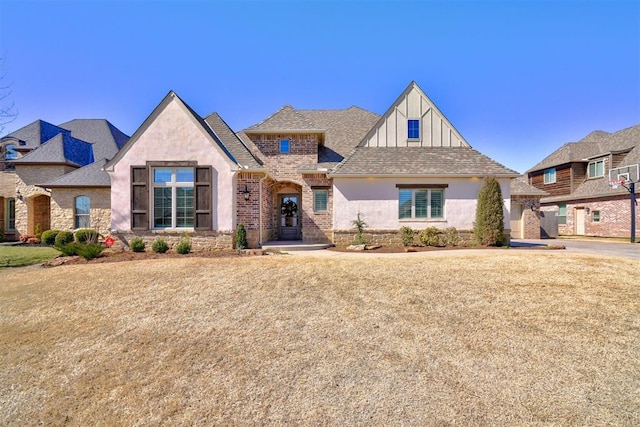 view of front of house featuring brick siding, a front lawn, and roof with shingles