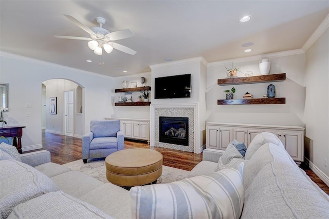 living area with light wood-style floors, arched walkways, a fireplace, and crown molding