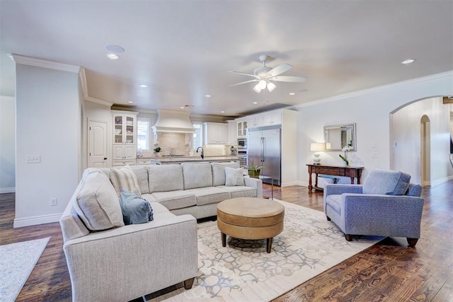 living area with arched walkways, recessed lighting, wood finished floors, baseboards, and ornamental molding