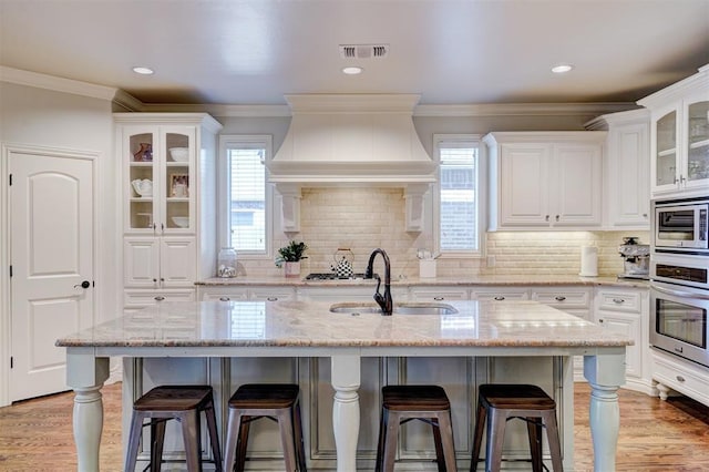 kitchen featuring stainless steel appliances, a sink, white cabinetry, visible vents, and custom range hood