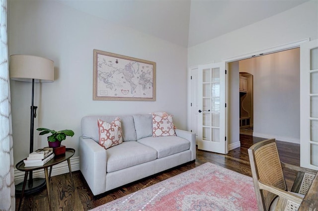 living area with baseboards, arched walkways, and wood finished floors