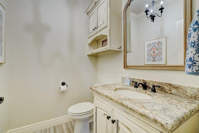 bathroom featuring crown molding, toilet, vanity, wood finished floors, and baseboards