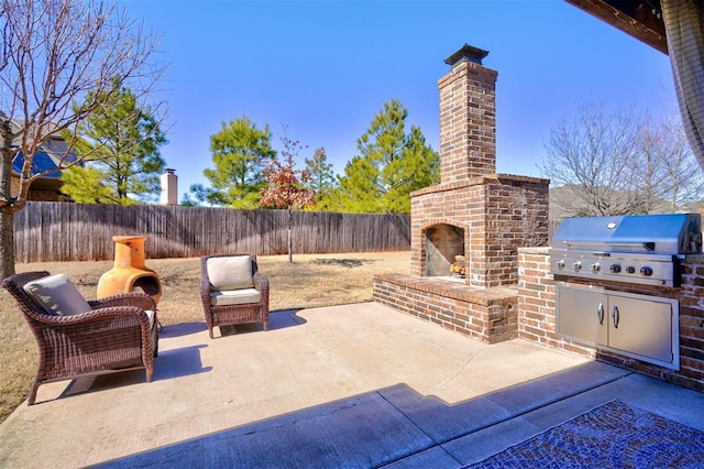 view of patio featuring a fenced backyard, area for grilling, and an outdoor brick fireplace