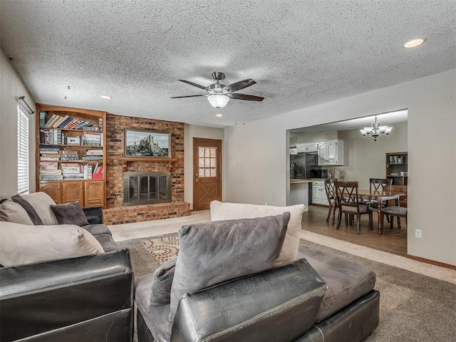 living room with a textured ceiling, carpet floors, ceiling fan with notable chandelier, and a brick fireplace