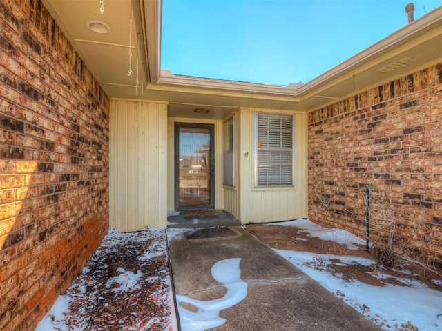 snow covered property entrance with brick siding