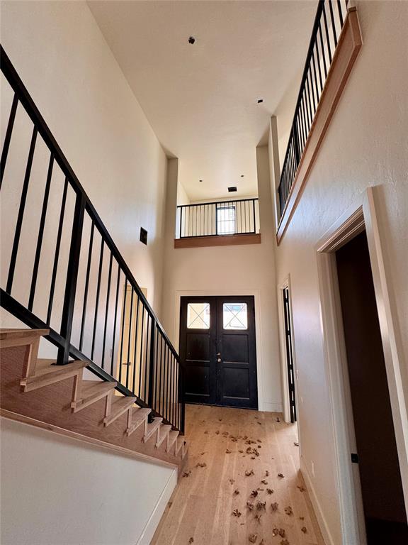 foyer entrance with french doors, a high ceiling, wood finished floors, baseboards, and stairs