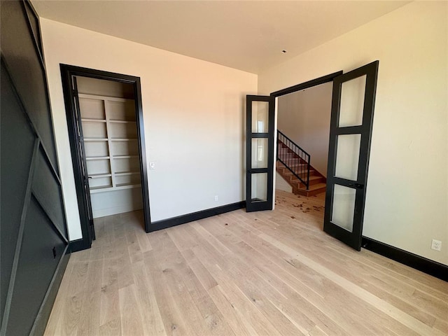 unfurnished bedroom featuring light wood finished floors, baseboards, and french doors