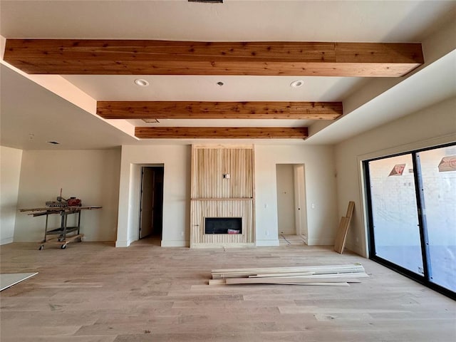 unfurnished living room featuring light wood finished floors, a fireplace, beam ceiling, and baseboards