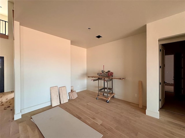 empty room with wood finished floors, visible vents, and baseboards