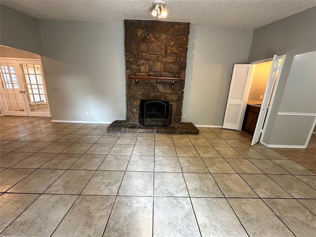 unfurnished living room featuring light tile patterned flooring, a fireplace, a textured ceiling, and baseboards