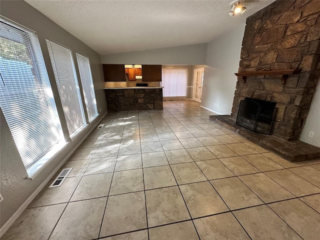 unfurnished living room with light tile patterned floors, visible vents, a textured ceiling, and vaulted ceiling