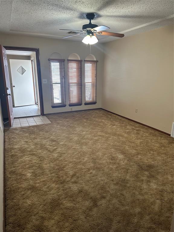 spare room with ceiling fan, light carpet, and a textured ceiling