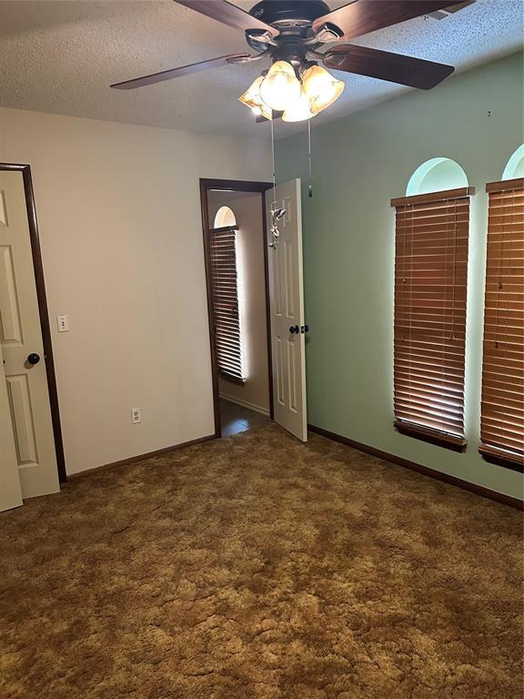 carpeted empty room with ceiling fan and a textured ceiling