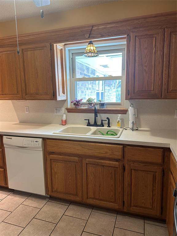 kitchen with sink, dishwasher, hanging light fixtures, and light tile patterned floors