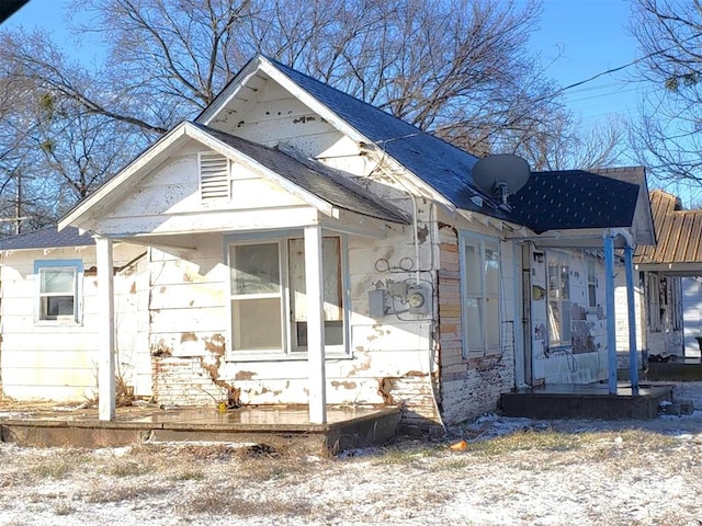 view of side of property with a porch and roof with shingles