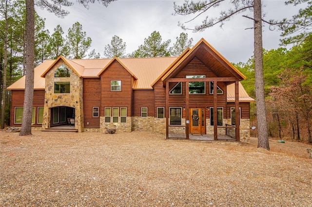 view of front facade featuring faux log siding, stone siding, and metal roof